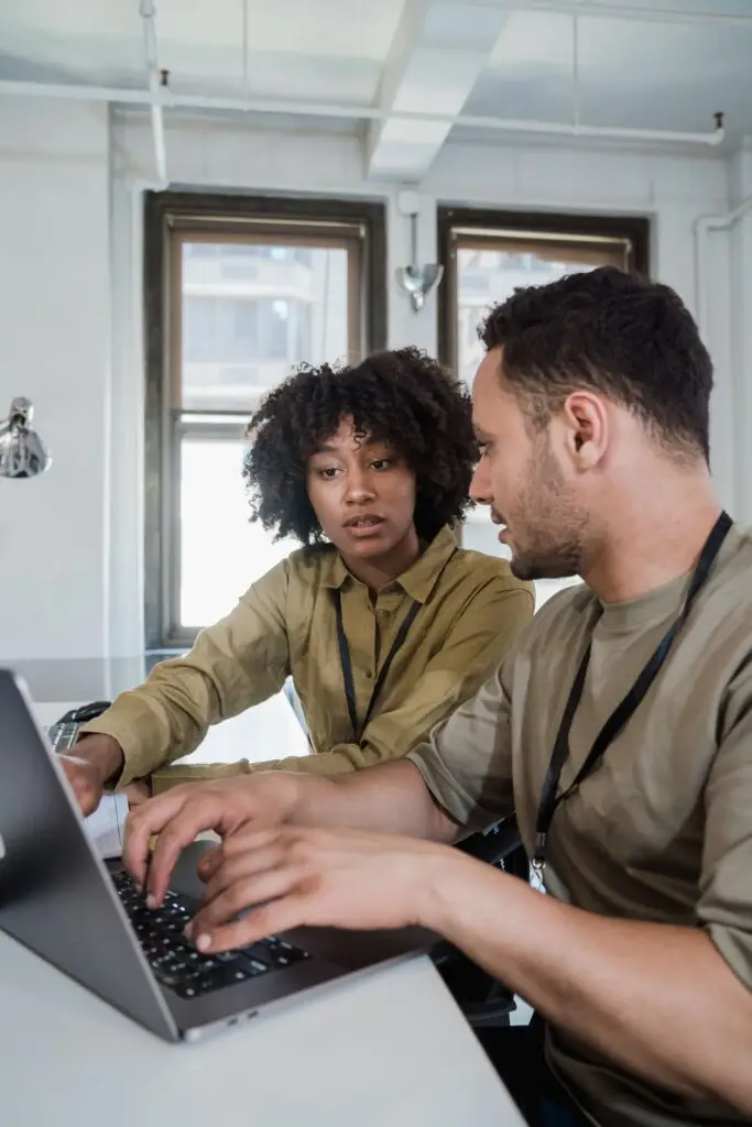 Two colleagues working together on a laptop in a small office