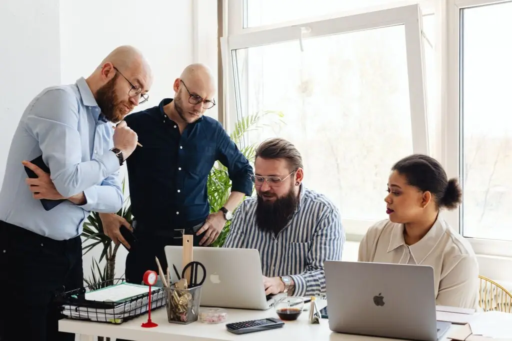 Team collaborating around a laptop in a modern office